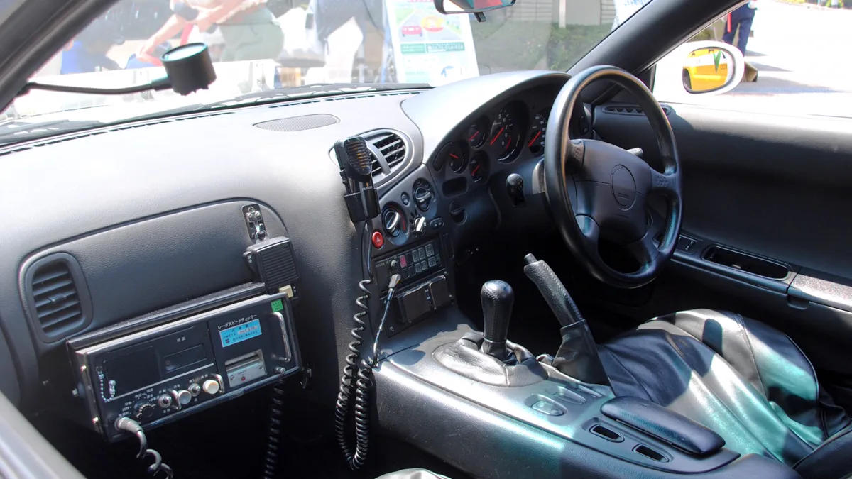 Driver perspective of right hand drive Japanese vehicle interior highlighting analog gauges and manual gearshift