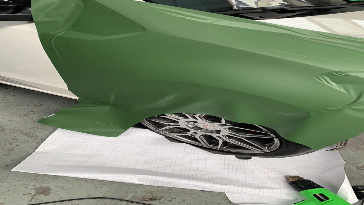 Technician applying vinyl wrap to car door panel illustrating how much does it cost to wrap a car