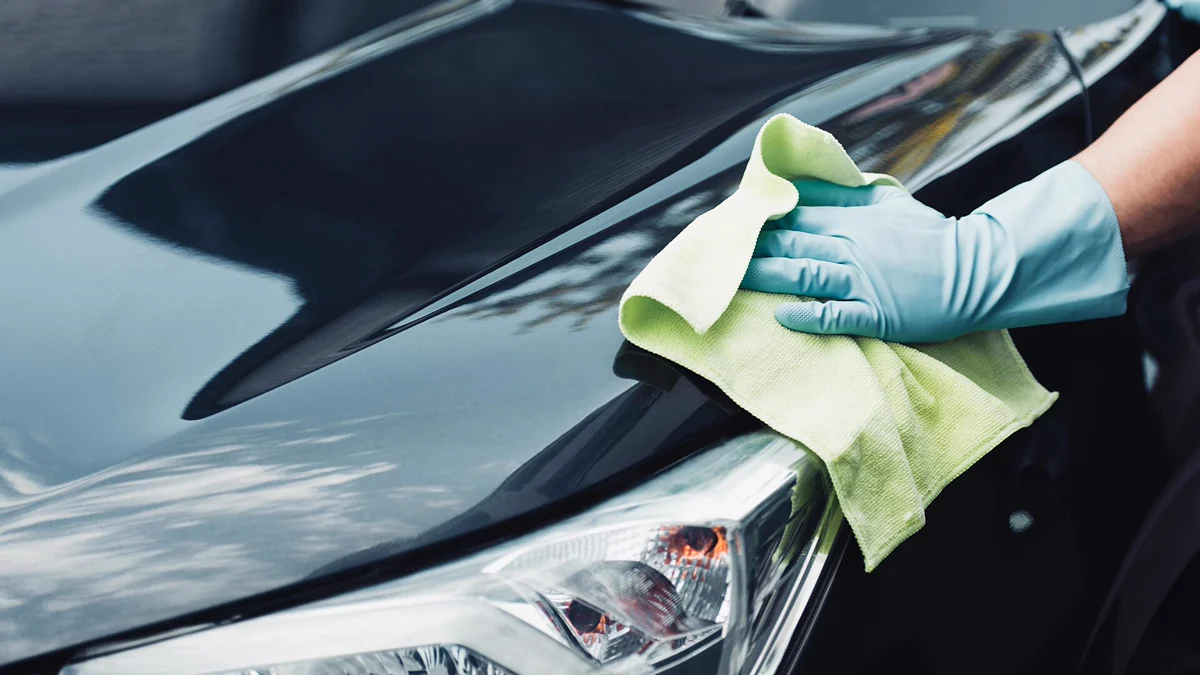 Fabric shampoo and cleaner application on cloth car seats Agitating upholstery cleaner across car seat fabric with soft detailing tools