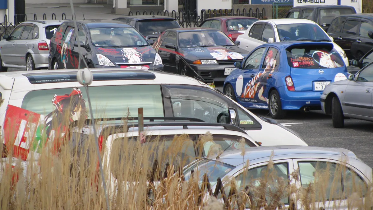 Enthusiast gathering of modified vehicles showcasing varied anime car wrap styling