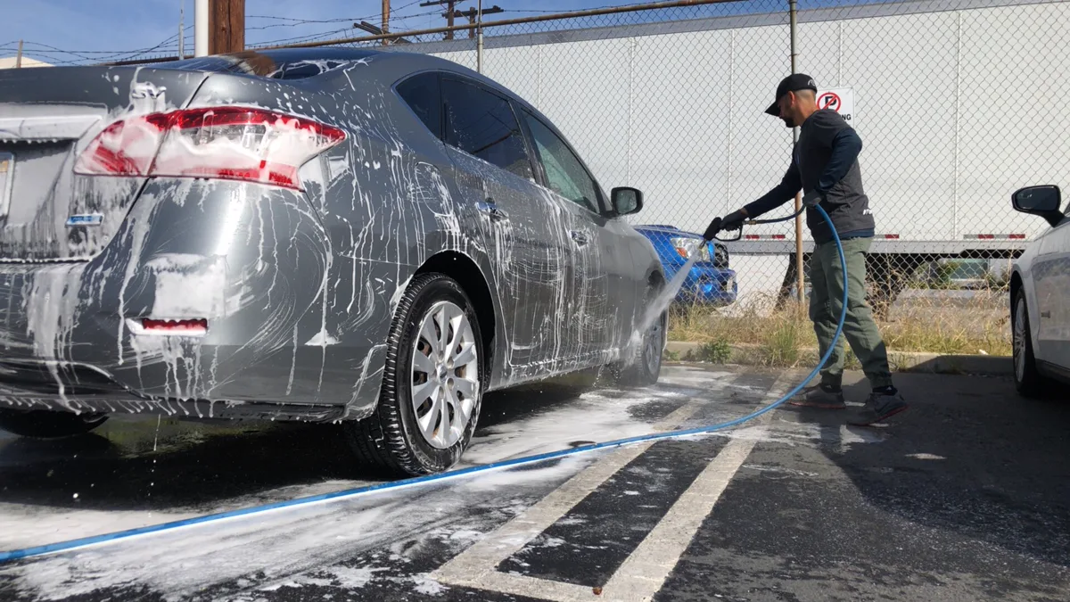 Gentle hand washing of wrapped automotive panels using microfiber mitt and suds Technician hand washing vehicle with microfiber sponge demonstrating how to wash a wrapped car safely