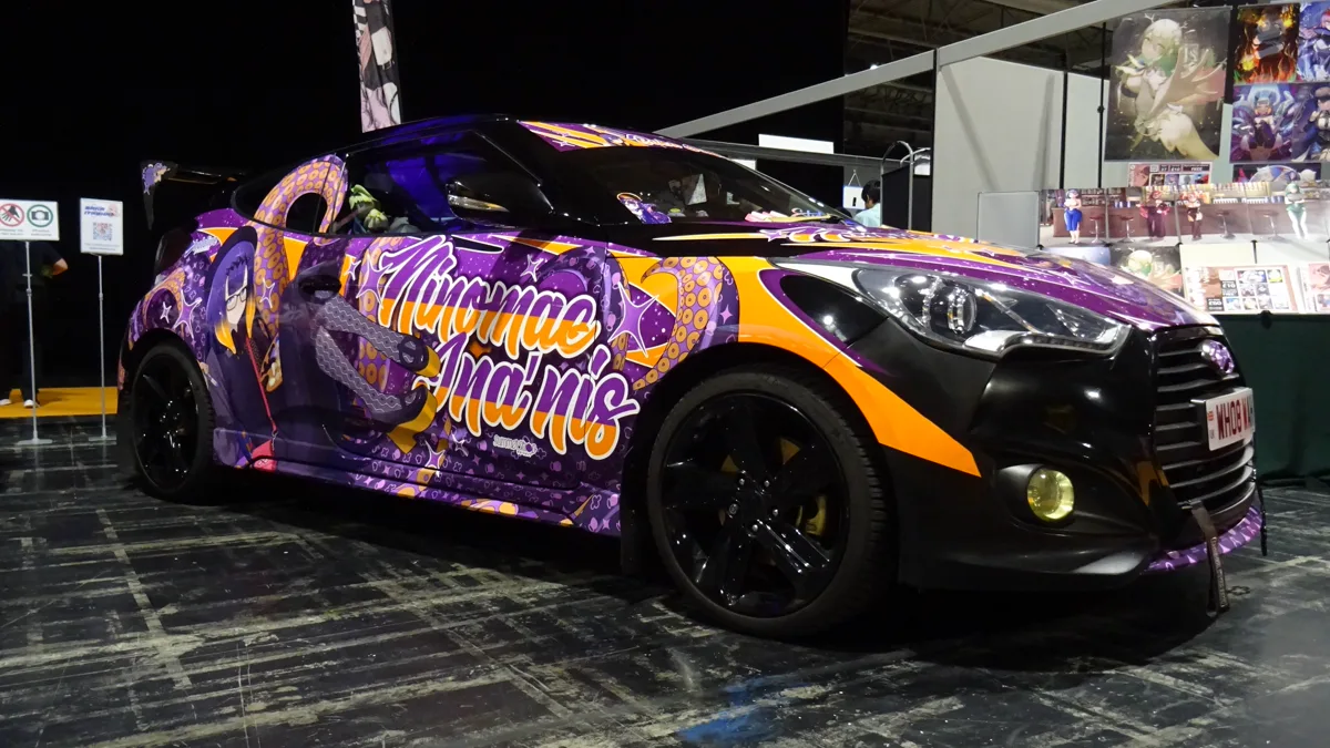 Full body graphics on modern hatchback displayed at an automotive culture expo